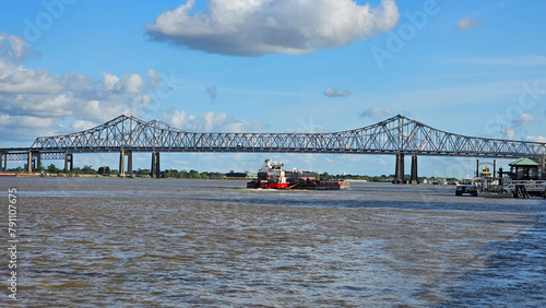 a gorgeous summer landscape along the Mississippi River with the Crescent City Connection bridge over the water with blue sky and powerful clouds at sunset in New Orleans Louisiana USA