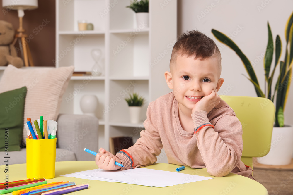 Cute little boy drawing with felt-tip pens at table in room Cute little boy drawing with felt-tip pens at table in room