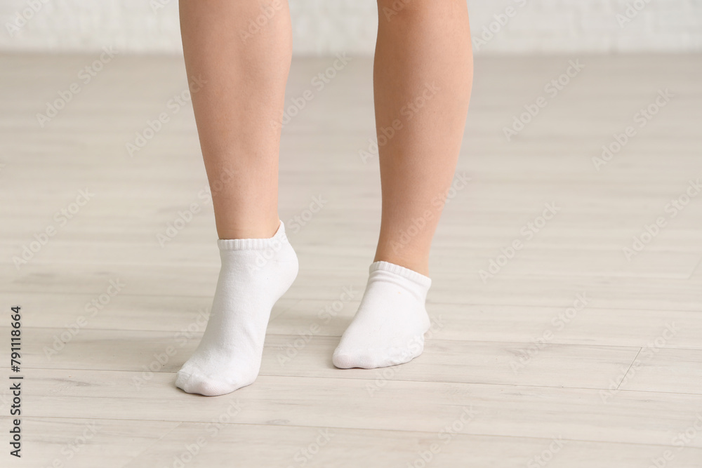 Woman in socks walking on laminate floor at home, closeup