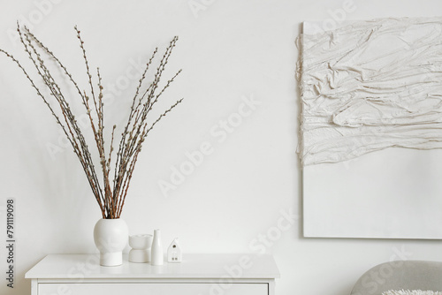 Vase with willow branches on commode in light living room photo