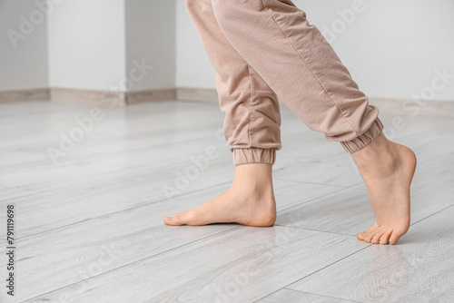Barefoot woman walking on laminate floor in light room, closeup