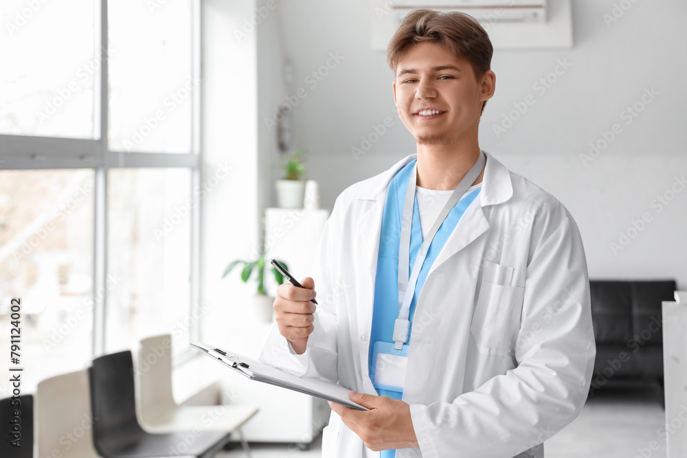Male medical intern with clipboard near window in clinic Male medical intern with clipboard near window in clinic