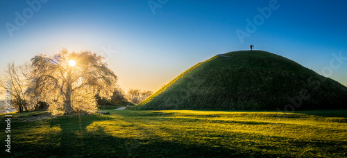 Sunset over blossoming plum tree and Krakus Mound with lonely man during Spring, Krakow, Poland. photo