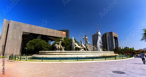 Lockdown Time Lapse Shot Of Famous Fuente De Neptuno At Macroplaza Near Buildings Against Clear Blue Sky - Monterrey, Mexico photo