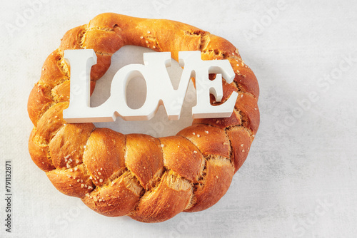 challah, braided bread ring. Round white wheat bread with coarse salt and the inscription Love. The concept of love for bread, fighting hunger in developing countries.