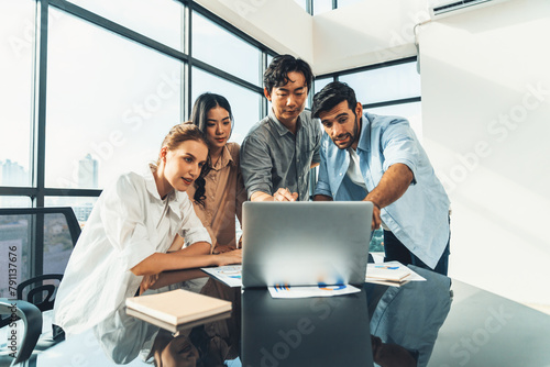 Asian project manager uses laptop displayed data analysis while professional business team brainstorming marketing idea at business meeting. Working together,sharing idea, planing strategy. Tracery. © Summit Art Creations