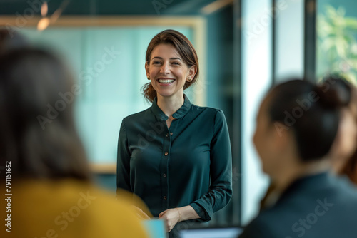 Confident businesswoman leading a meeting. A smiling businesswoman confidently addresses her team during a meeting in a modern office setting.