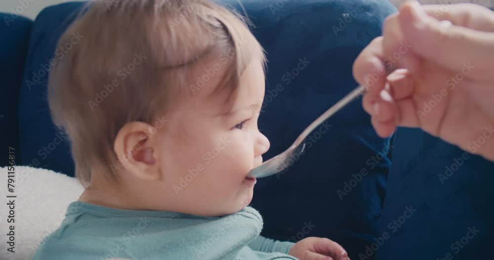 baby boy eating yogurt off of a spoon on the couch baby boy eating yogurt off of a spoon on the couch