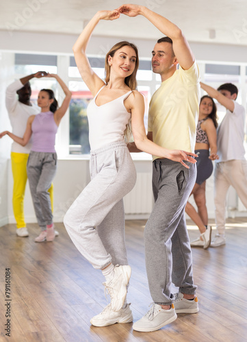 Man and girl are standing next to each other and dancing in pair of salsa. Students practice repeating movements of pair dance