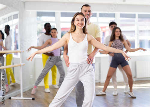 With unhurried music, man with young woman in couple spins to rhythm of waltz during lesson for novice students. Classes in mini-groups for those who want to learn dancing