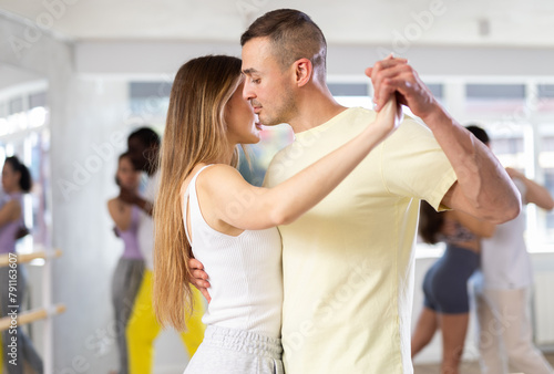 Fototapeta Naklejka Na Ścianę i Meble -  With unhurried music, man with young woman in couple spins to rhythm of waltz during lesson for novice students. Classes in mini-groups for those who want to learn dancing