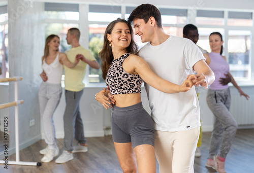 With unhurried music, young man with woman in couple spins to rhythm of waltz during lesson for novice students. Classes in mini-groups for those who want to learn dancing