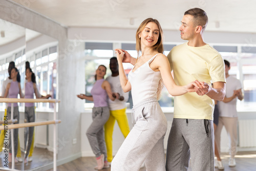 Smiling ordinary adults dancing bachata together in dance studio