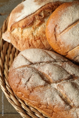Basket with different types of fresh bread on table, closeup