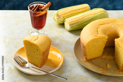 Corn cake on a plate on a yellow marble table, ears of green corn on the table