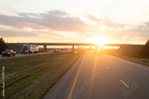 Peaceful Sunset View on Highway with Vehicles Driving Under Overpass © KirKam