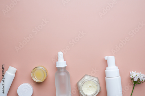 The skincare and cosmetic with flower on pink or neutral flatlay background
