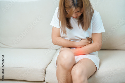woman having abdomen ache due to Stomach pain, digestion with constipation or Diarrhea from food poisoning, female problem and Endometriosis, Hysterectomy, Stomachache and Menstrual on sofa at home