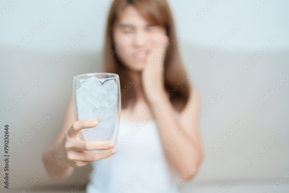 Teeth Sensitive to Cold concept. woman hold Ice Water glass and having toothache and pain after eat. Tooth Decay or Gum Disease, Grinding Teeth and Stress, Exposed Nerve Roots, Crack and Receding Gums Teeth Sensitive to Cold concept. woman hold Ice Water glass and having toothache and pain after eat. Tooth Decay or Gum Disease, Grinding Teeth and Stress, Exposed Nerve Roots, Crack and Receding Gums