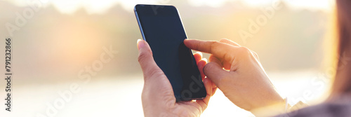 Banner Woman hands holding mobile phone outdoor surfing internet online technology lifestyle. Close up woman hand using smartphone gadget text message panoramic with copy space. Technology lifestyle © aFotostock