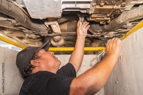 Fotografia Mechanic looking into the engine of a car standing underneath