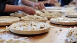 Close-up of a pie workshop, with participants crimping edges of their pies, showcasing the detail and technique, on a baking station. 
