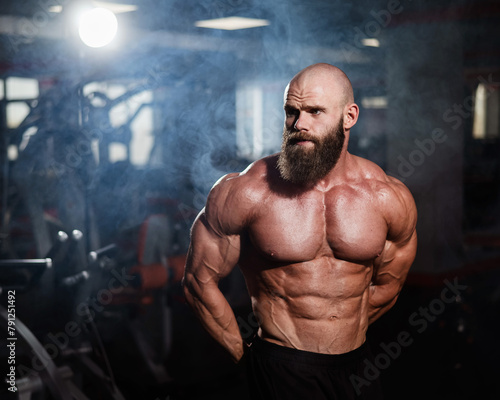 Muscular bald man posing shirtless. Bodybuilder showing off his shape in the gym.  © Михаил Решетников