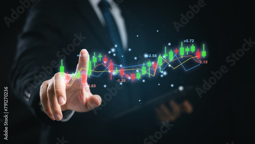 A man wear suit is pointing at a stock exchange graph for trading and analysis on a virtual screen. Concept of investment, market trend forecast and financial analyze.