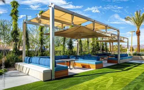 an outdoor patio with blue and white seating, under the shade structure made from light wood and beige color © Kien