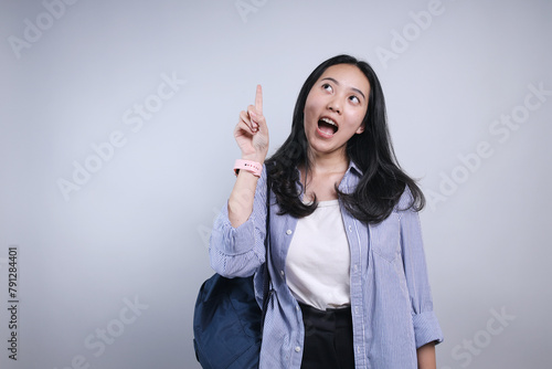 Smart Young Female Student Getting an Idea Showing Aha Moment Pointing Up Forefinger Isolated On White Background photo