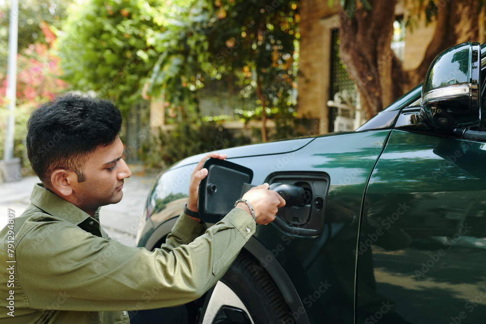 Indian electric car owner charging his vehicle Indian electric car owner charging his vehicle
