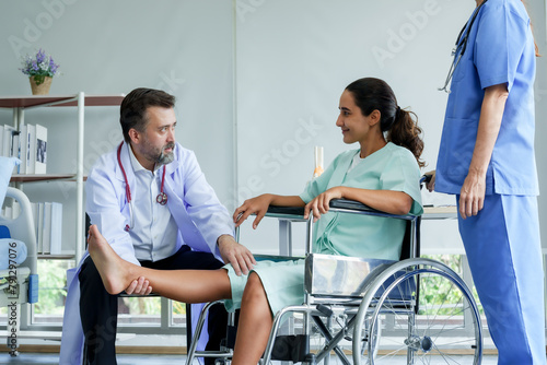 Male orthopedic doctor injury test Lifting the legs of Hispanic female patient with a wheelchair Lift your leg up and down to check for injuries. prepare for physical therapy with physical therapist.