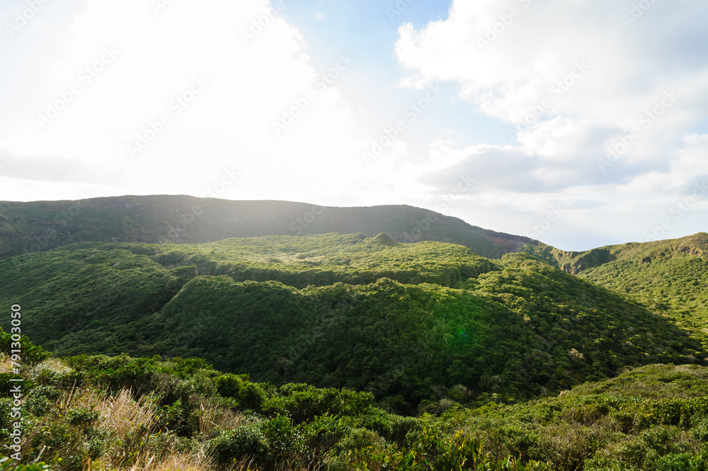 Naklejka premium 標高854mの八丈島最高峰、八丈富士の登山トレッキング。 八丈富士の山頂は大きなカルデラになっている。 カルデラの縁をぐるりと一周する「お鉢めぐり」をすることができる。 太平洋とカルデラ内部の景色は雄大。 険しい崖の上を歩くので要注意。強風時は立ち入り禁止。航路の終点、太平洋の大きな孤島、八丈島。 東京都伊豆諸島。 2020年撮影。Trekking up the 854-meter-hi