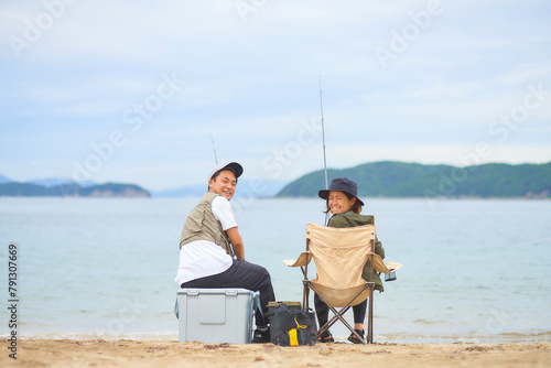 浜辺で座って釣りをする男女 photo