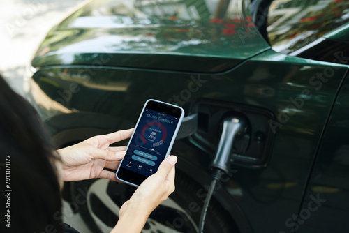 Woman controlling electric car charging level via mobile app