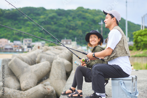 堤防で座って釣りをする男女 photo