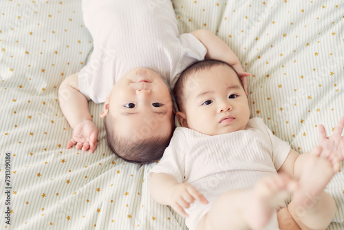 布団の上に寝転ぶ双子の赤ちゃん photo