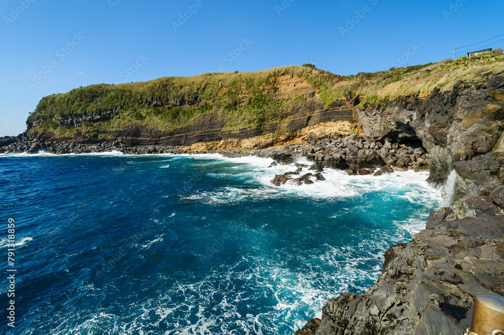 Fototapeta premium 太平洋の荒波を受ける島南岸の藍ヶ江海水浴場の防波堤外。 海の色が凄まじく美しいブルー。航路の終点、太平洋の大きな孤島、八丈島。 東京都伊豆諸島。 2020年撮影。Outside the breakwater of Aigae Beach on the south shore of the island, which is subject to the rough waves of the
