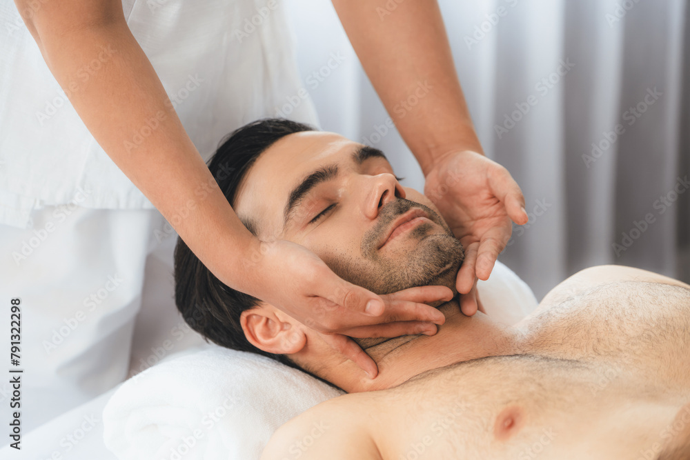 Naklejka premium Caucasian man enjoying relaxing anti-stress head massage and pampering facial beauty skin recreation leisure in dayspa modern light ambient at luxury resort or hotel spa salon. Quiescent