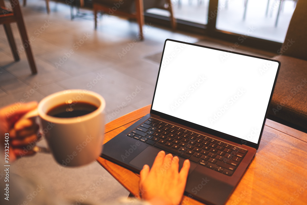 Mockup image of a woman using and working on laptop computer with blank white desktop screen while drinking coffee Mockup image of a woman using and working on laptop computer with blank white desktop screen while drinking coffee