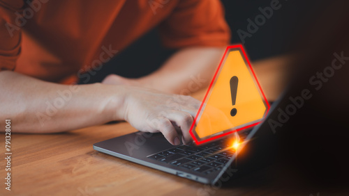 A caution warning sign alerts the user while using a computer laptop, emphasizing the importance of cyber security in detecting viruses, protecting personal data, and maintaining network security. © ParinPIX