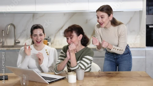 Women are sitting at computer and are immensely happy, exclaim joyfully and are fortunate to receive good news about win photo
