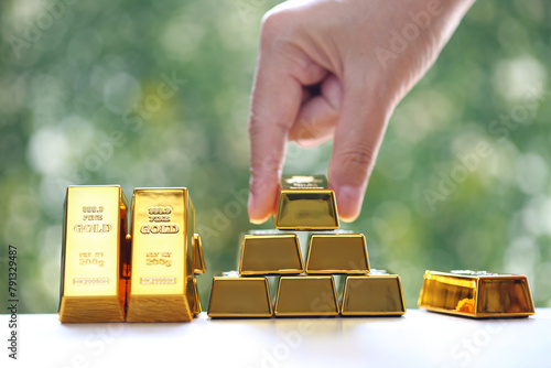 Woman hand hold the gold bar on natural green background, investment and business concept photo