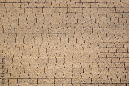 The surface is made of sand-colored paving slabs of trapezoidal and rectangular shape.
