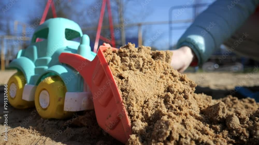 Little boy plays in the sandbox with his mother, a dump truck and a tractor Little boy plays in the sandbox with his mother, a dump truck and a tractor