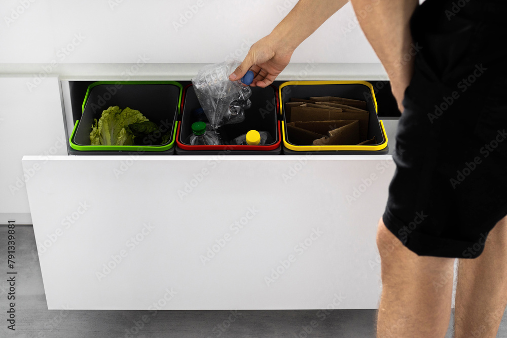 A young man sorts garbage in containers in the kitchen in slow motion ...