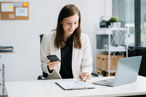Confident business expert attractive smiling young woman typing laptop and holding digital tablet .
