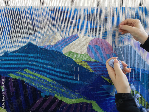 Woman's hands making tapestry with colorful wool