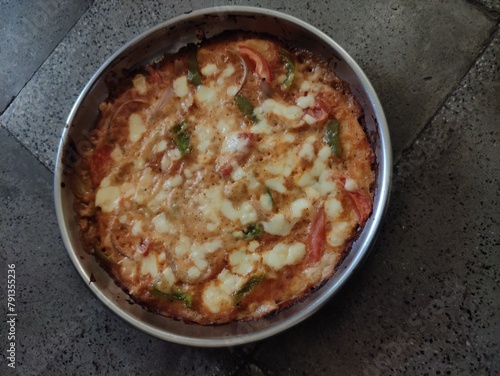 Pizza with cheese and tomatoes on tile floor.