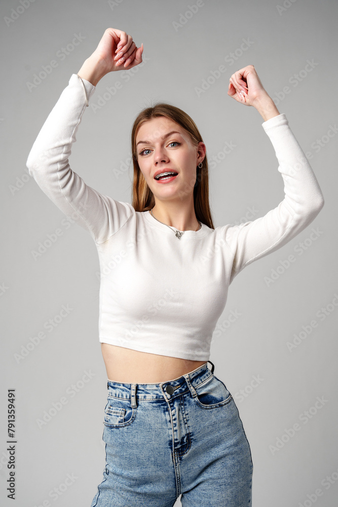 Young Woman Dancing Joyfully Against a Gray Backdrop